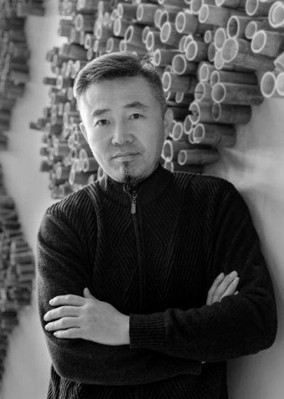 a picture of artist liu wei standing in front of artwork, his arms are crossed in front of him